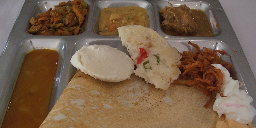 South Indian thali with dosa, idli, sambar, chutney, and other items served on a plate.