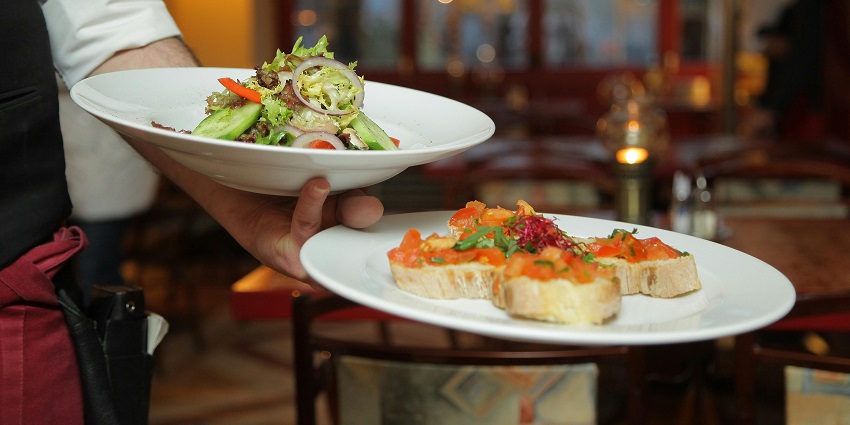 A person holding two types of dishes served on a white plate ceramic in a single hand
