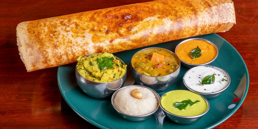 Traditional South Indian meal with idli, medu vada, sambar, and chutney on a Banana leaf.