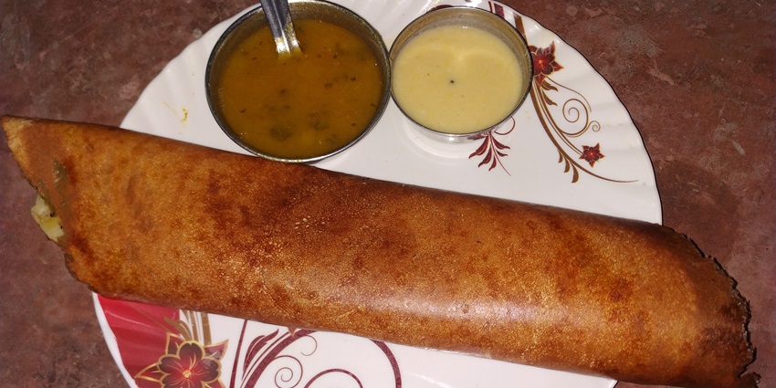 An image of butter dosa served with coconut chutney and sambhar.