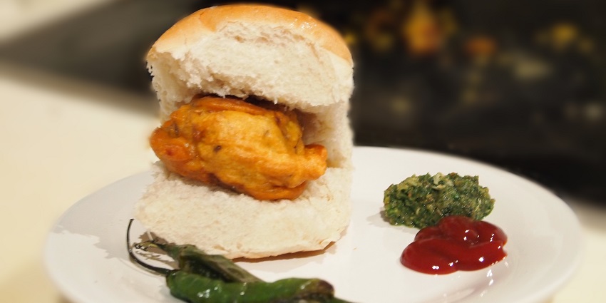 Image of delicious vada pav with green chilli pepper, a famous food item in Maharashtra.