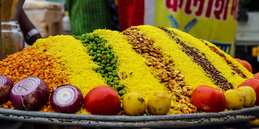 An assortment of Indian food served on a large silver platter featuring a mix of crispy snacks.