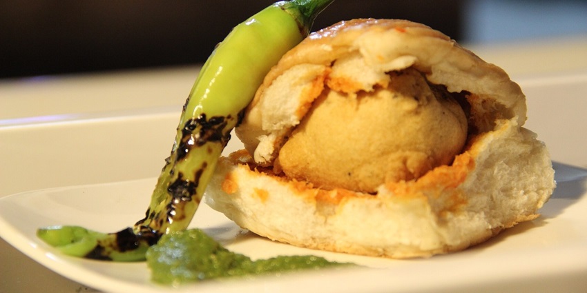 A delicious vada pav with green chilli pepper, a traditional Maharashtrian snack.