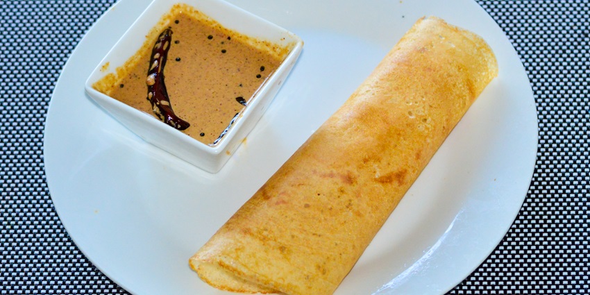 Dosa, on a plate, sambar in a bowl with coconut chutney, served all in one tray