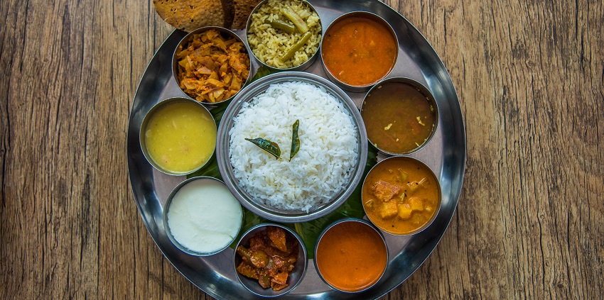 South Indian cuisine which includes various dishes is served on a leaf with accompaniments