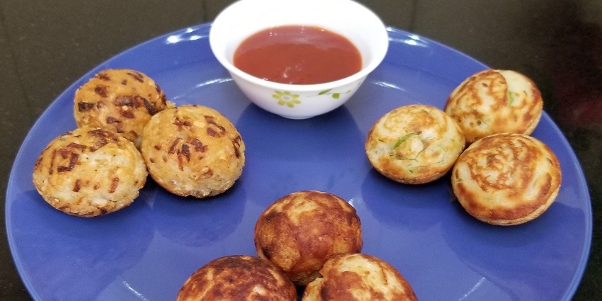 Fresh and crispy Kuzhi Paniyaram served with chutney on the side on a plate.