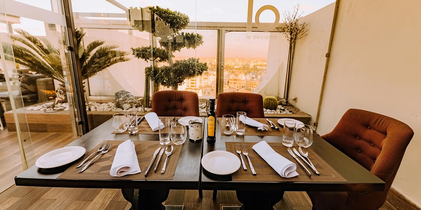 A variety of eating cutlery is placed on a wooden table with a magnificent view of a clear sky