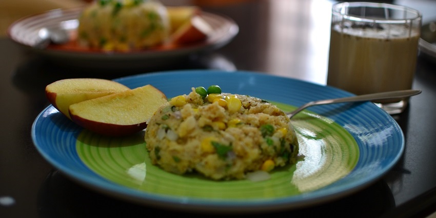Upma served on a plate with two apple slices to have during Dhyanalinga Temple trip.