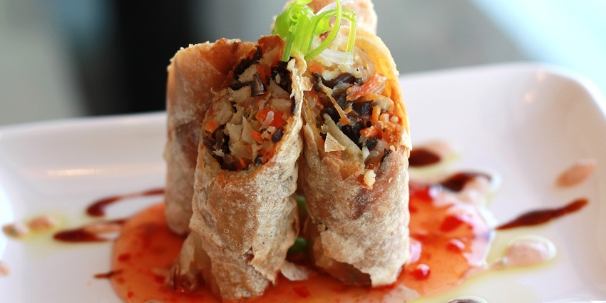 Cut pieces of spring rolls filled with assorted vegetables served on a white plate