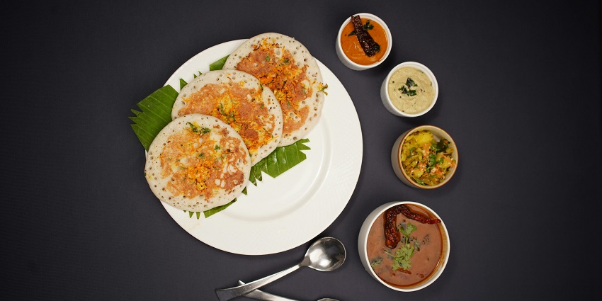 Image of a meal served on a plate with chutney on the side presented on a table