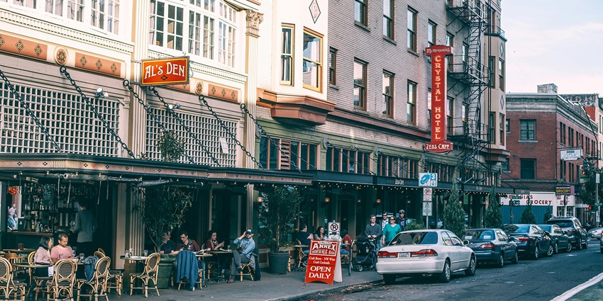An image showing a house featuring a cafe and restaurant, with parked cars in the city.