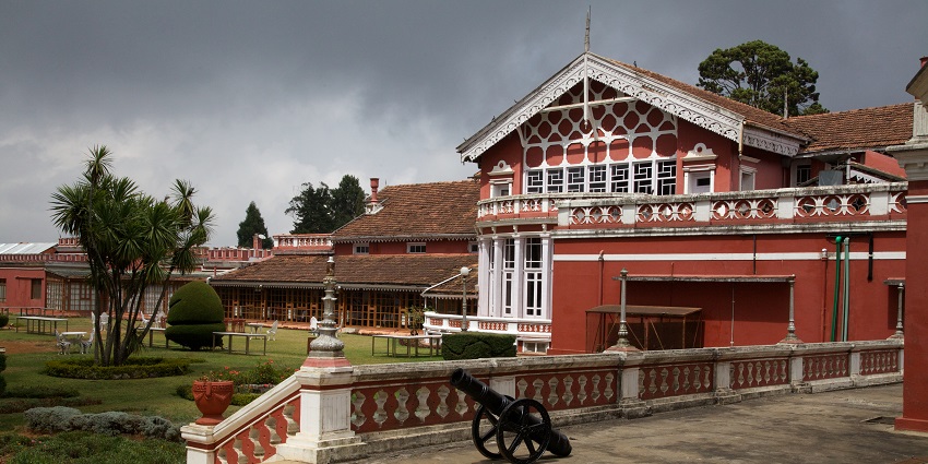 Fernhills Palace Hotel in Ooty, showcasing its grand colonial architecture amidst lush greenery.