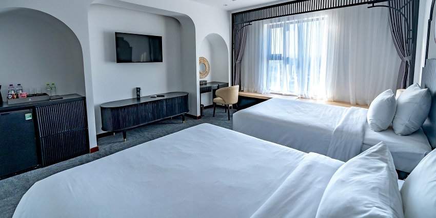 An image showing two beds and natural light in a contemporary hotel room