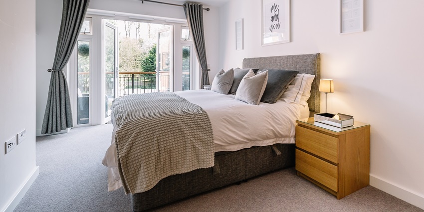 A bedroom with a large bed, soft pillows, and warm lighting featuring stylish furniture.