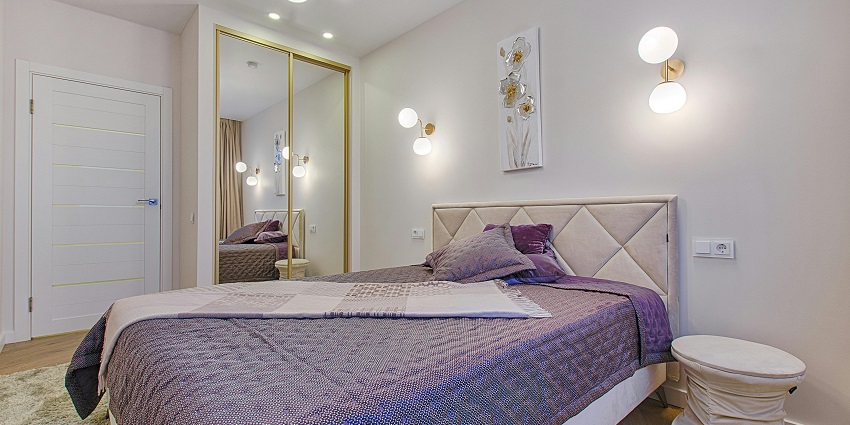 A view of a bed in a hotel room near Agaya Gangai Waterfalls covered with a purple blanket.