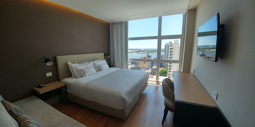  Inside view of a hotel room with large glass windows featuring a bed and a television
