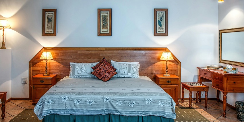 A view of a bed in a hotel room near Funtasi Water Park with white walls.