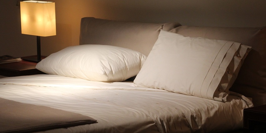 Stylish double bed adorned with colourful cushions in a cosy bedroom setting.