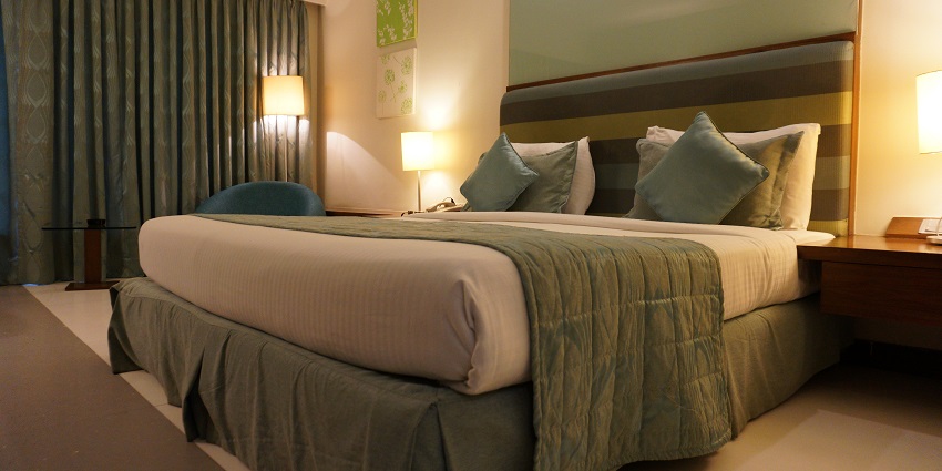 Hotel room with a bed, bedside lamp, and large window