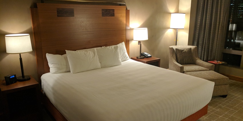 A luxury hotel room with a large bed, elegant furnishings, soft lighting, and a big window