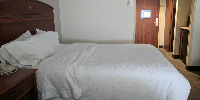 A hotel room with a neatly made bed, and modern furnishings near Peruvudaiyar temple.