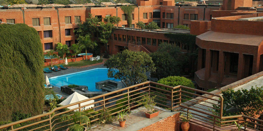 Elegant hotel with glass doors and a swimming pool near Sikandra Fort