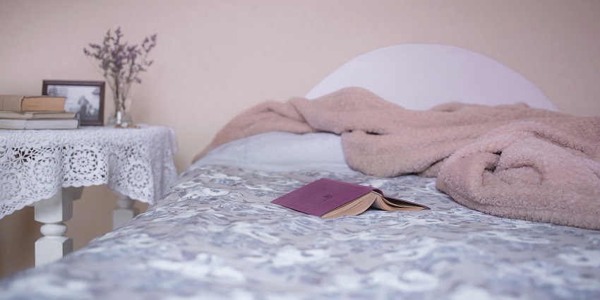 Cosy bedroom with a neatly made bed and a colourful blanket draped over it