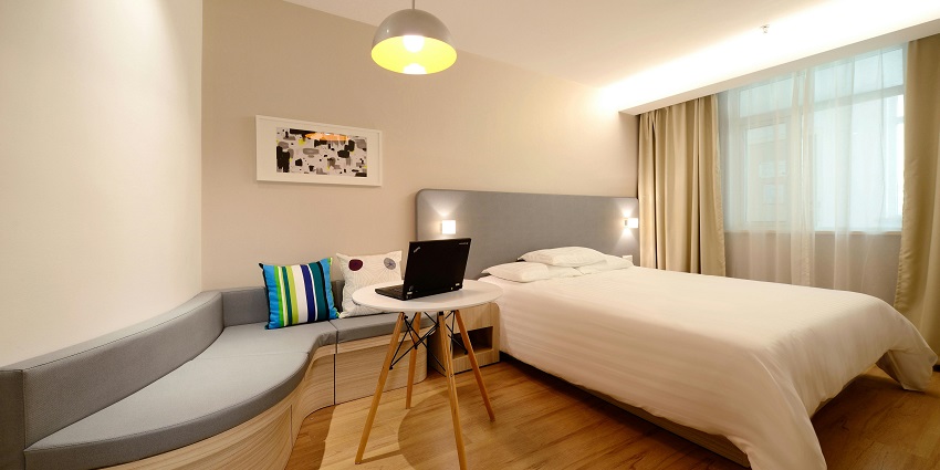 Stylish hotel bedroom with a comfortable workspace, perfect for relaxation and productivity.