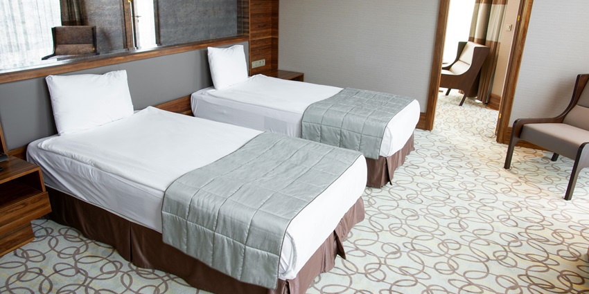 A hotel room with drawers beside the beds, a huge mirror and a floor with a unique design.
