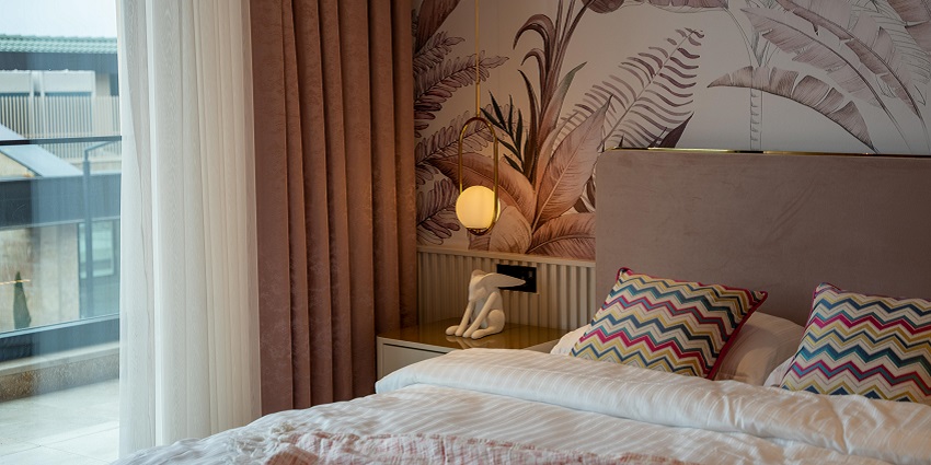 An inside view of a well-lit room with two single beds and lamps placed on the sides