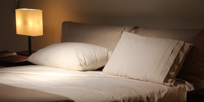 An image of a stylish double bed adorned with colourful cushions in a cosy bedroom setting.