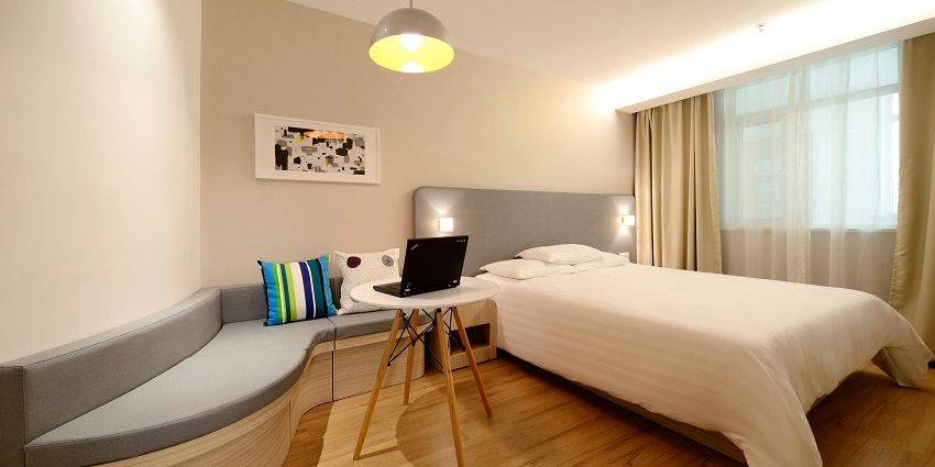 Stylish hotel bedroom with a comfortable workspace, perfect for relaxation and productivity.