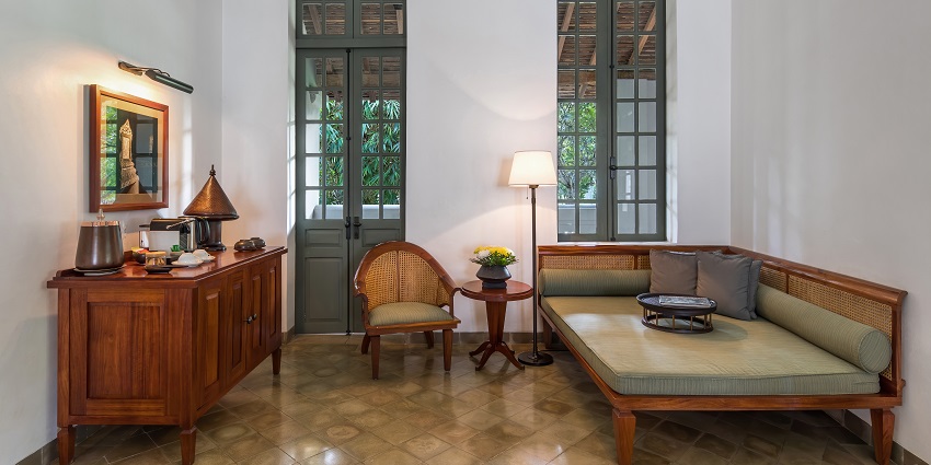 Lobby and lounge of a hotel with big windows, chairs and a painting against the wall.