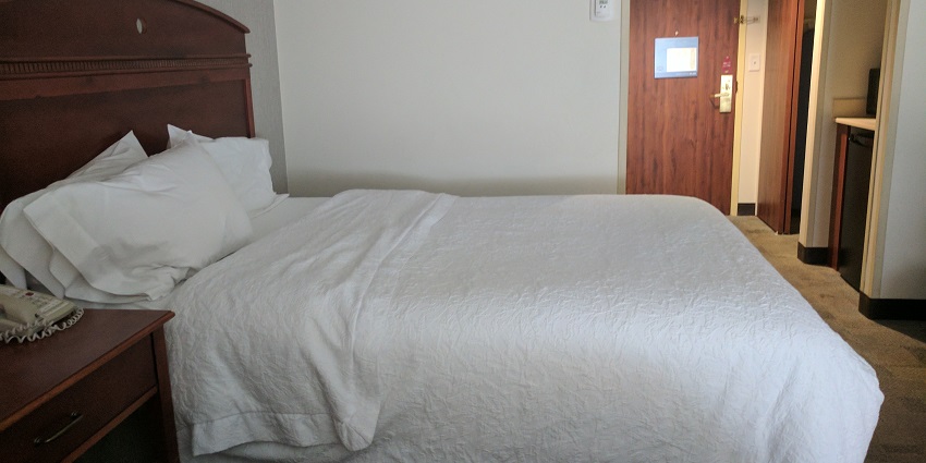 A modern hotel room with a television and plush bed to stay near Panduranga temple.