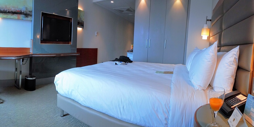 A modern hotel room with a television and plush bed, among other amenities