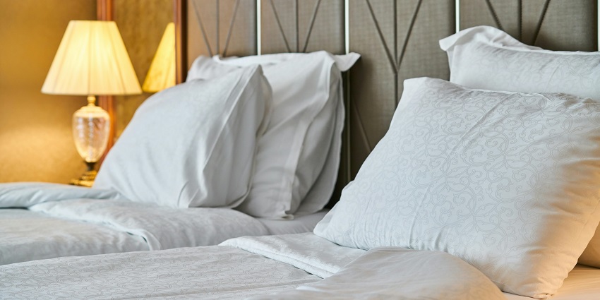 White bed sheet set neatly arranged on a bed with soft lighting, creating a peaceful atmosphere
