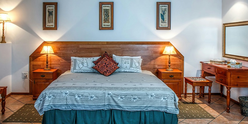 A view of a bedroom in a hotel with white bedding and a rustic stone wall