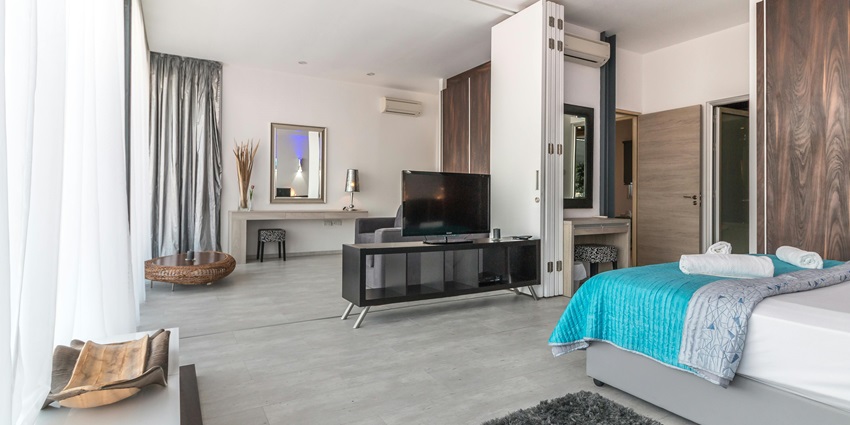 A stylish modern bedroom featuring a cosy bed, elegant decor, and warm lighting.