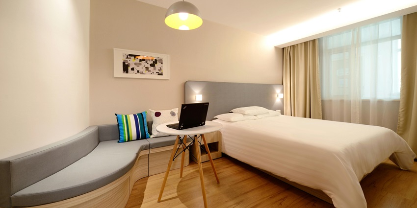 Stylish hotel bedroom with a comfortable workspace, perfect for relaxation and productivity.