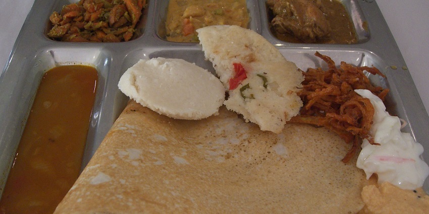Idli dosa served on a plate with chutneys and sambar in a traditional South Indian style.