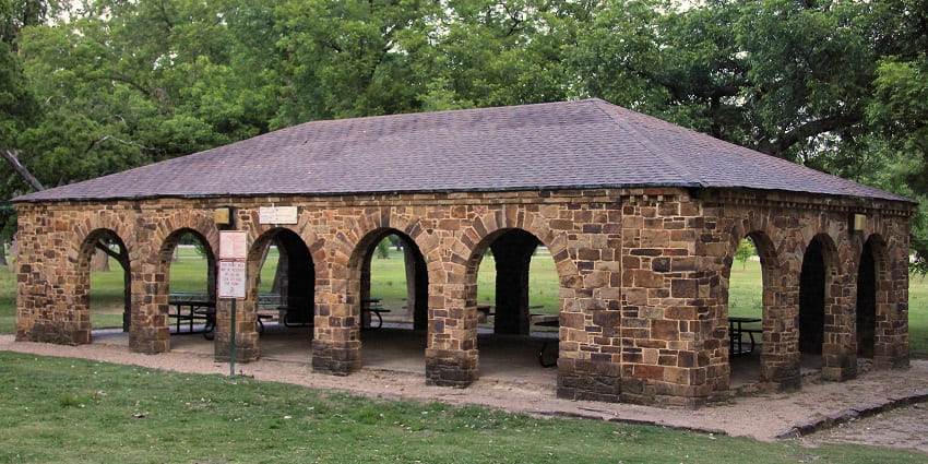 A pavilion inside of white rock lake park with a signboard and surrounded by greenery