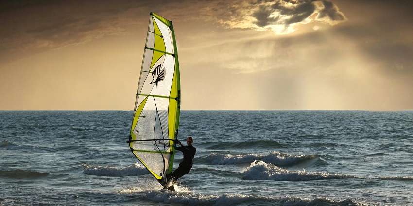 An image of a windsurfer gracefully gliding, one of the best Juhu Beach water sports.