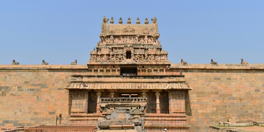 A breathtaking landscape of a temple in Kumbakonam with a woman in front during the day.