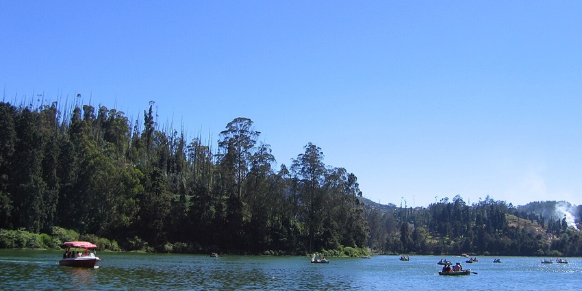An image of Ooty Lake with a hill in the background along with some boats in the lake