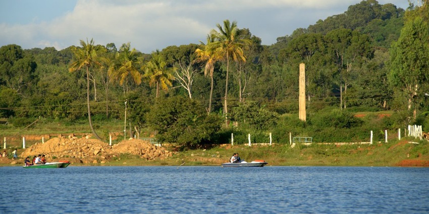 Image of Yelagiri Lake surrounded by lush greenery and a boat on the lake with people on it