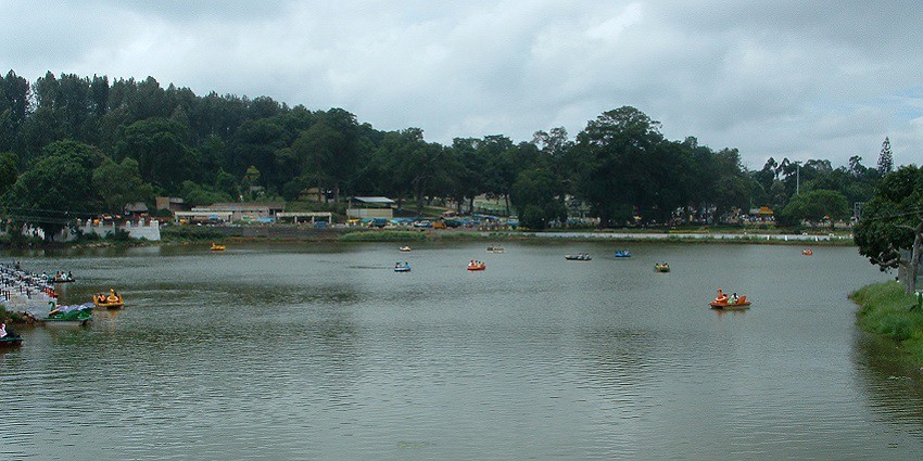 A view of Yercaud Lake with trees and hills in the background, located in Yercaud.