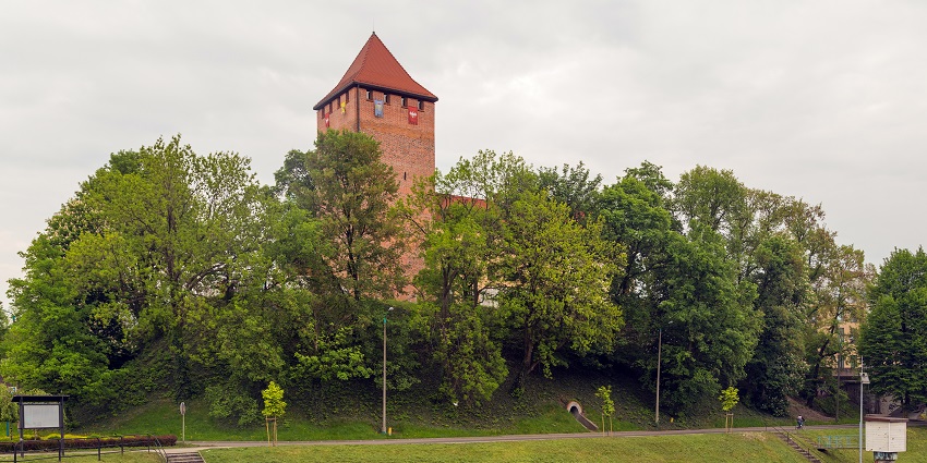 Oświęcim Castle with the tall tower, surrounded by green near Auschwitz-Birkenau State Museum.