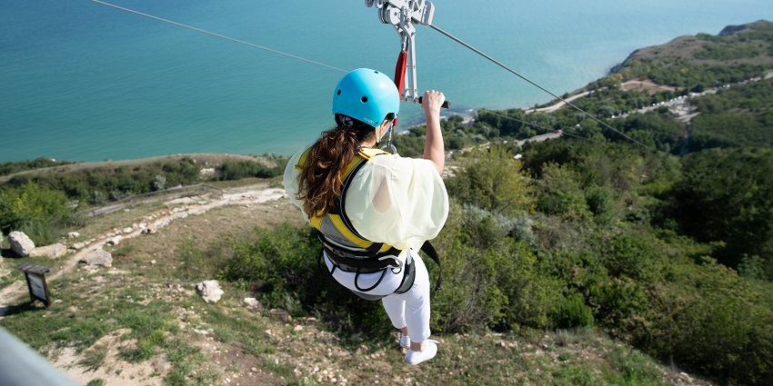 View of a women zip lining through picturesque valleys down the cliffs