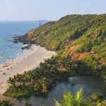 Scenic beach view from above, showing turquoise waters, sandy shore, and lush green surroundings