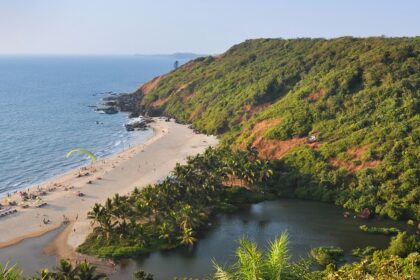 Scenic beach view from above, showing turquoise waters, sandy shore, and lush green surroundings